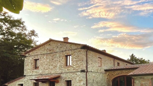 A stone building with a flat roof, multiple windows, and a small porch area. - Podere Cagnesi: Relaxation in nature (Podere Cagnesi)