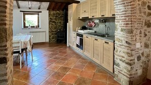 A rustic kitchen with stone walls, wooden beams, and a tiled floor. - Podere Cagnesi: Relaxation in nature (Podere Cagnesi)