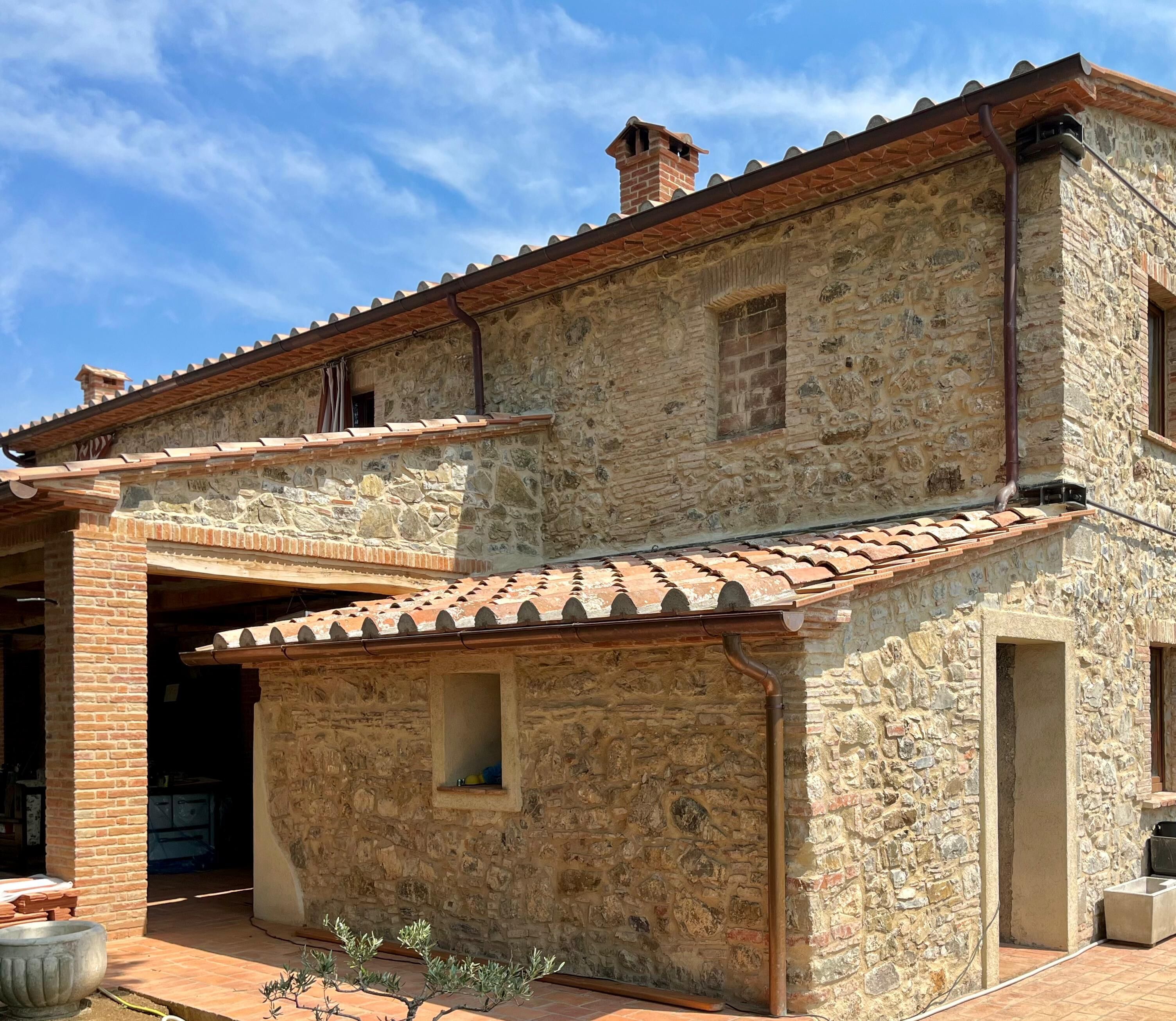 A stone building with a tiled roof, a small window, and a chimney.
