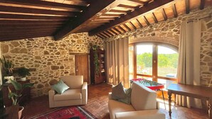 A cozy room with stone walls, wooden beams, a foosball table, and a large window with a view. - Podere Cagnesi: Relaxation in nature (Podere Cagnesi)
