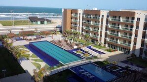 A hotel with a large swimming pool, a beach view, and a modern building with multiple balconies. - VG Fun Praia do Futuro (Fortaleza)