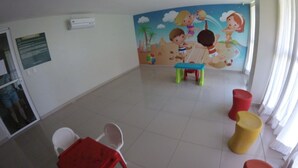 A room with a tiled floor, a mural with cartoon characters, and colorful stools. - VG Fun Praia do Futuro (Fortaleza)