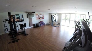 A spacious gym with a treadmill, stationary bikes, and weight machines. - VG Fun Praia do Futuro (Fortaleza)