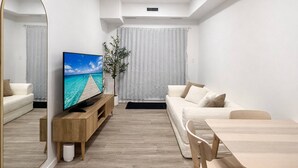 A modern living room with a wooden dining table, a sofa, a TV on a wooden stand, and a large mirror. - Condo w 2 Beds 13 Mins From West Edmonton Mall (Edmonton)