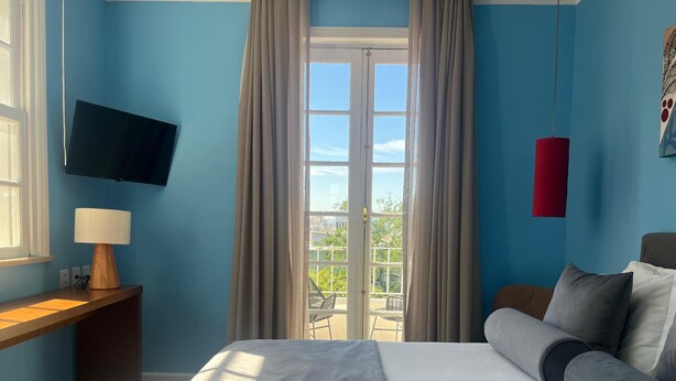 Una camera d'albergo con un letto, una televisione, una scrivania con una lampada e vista sull'esterno da una finestra.