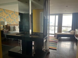A modern hotel room with a large mirror, two sinks, a sofa, and a view of the city. - Raro Ipanema Boutique Hotel (Rio de Janeiro)