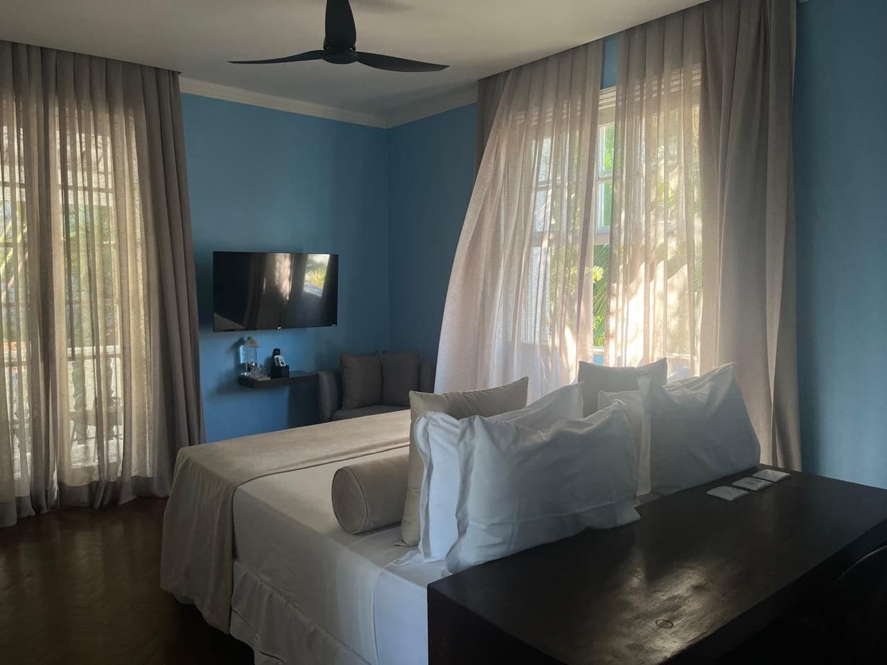 A hotel room with a bed, a desk, a TV, and curtains.