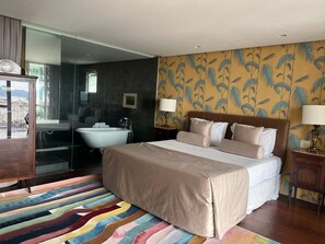 A hotel room with a large bed, a bathtub, a wooden nightstand, and a colorful striped rug. - Raro Ipanema Boutique Hotel (Rio de Janeiro)