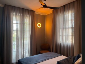 Una camera d'albergo con un letto, una sedia e una ventola a soffitto.
