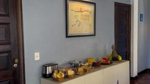 Un corridoio con una consolle bianca su cui sono esposti della frutta e un quadro appeso al muro.