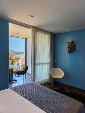 Una camera d'albergo con un letto, una sedia, un tavolo e vista sulla città.