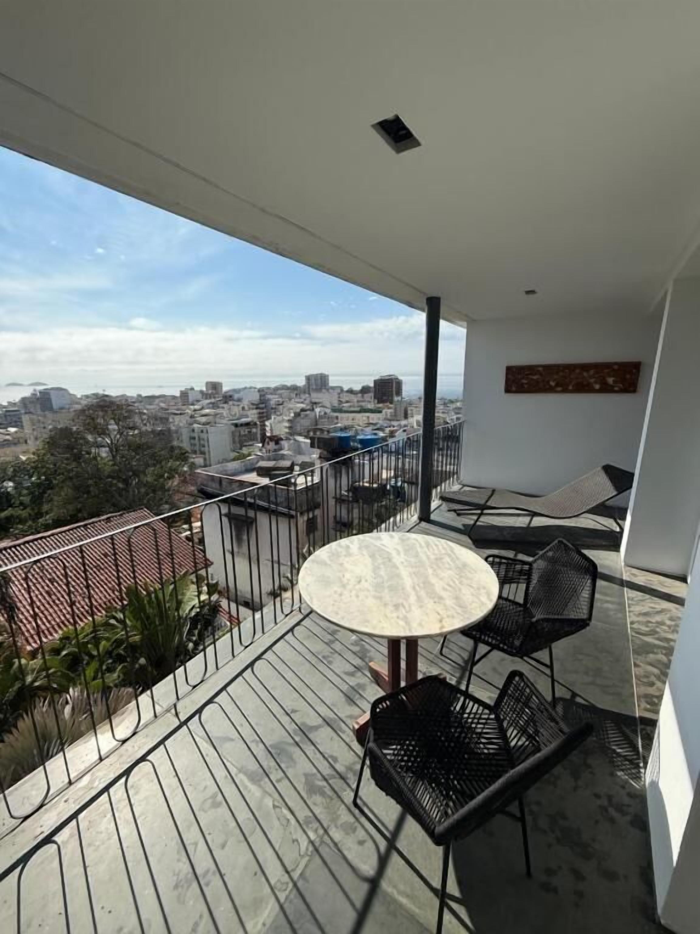 A balcony with a round table and chairs, overlooking a cityscape.