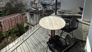 Un balcone con un tavolo rotondo e sedie, affacciato su un panorama urbano.
