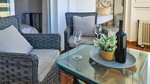 Un espace extérieur accueillant, aménagé avec des meubles en osier, une table en verre et une bouteille de vin.