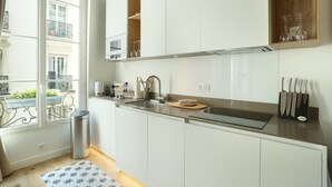 Een moderne keuken met witte kasten, een roestvrijstalen spoelbak en een raam met uitzicht op een balkon.