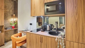 Cozinha compacta com armários de madeira, micro-ondas, chaleira e pia.