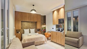 Quarto de hotel moderno com cama, sofá, cozinha compacta e vista para a cidade.