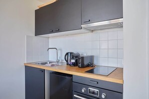 Cocina compacta con lavavajillas, cafetera y tostadora en la encimera.