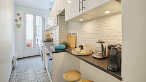 A modern kitchen with white cabinets, a black countertop, and a tiled backsplash. - Superb apartment Invalides Eiffel Tower (Paris)