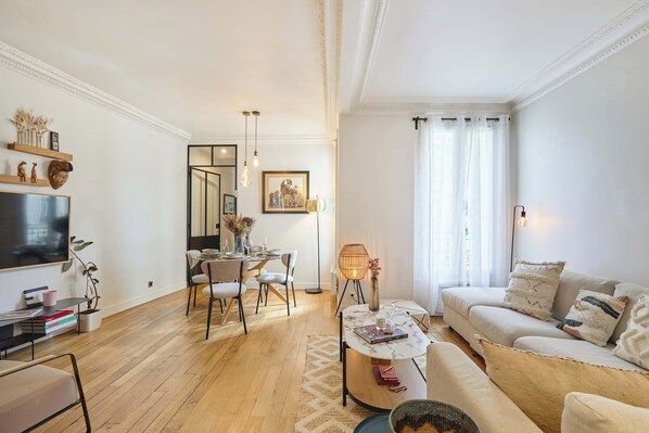 A modern living room with a sofa, coffee table, and dining area. - Superb apartment Invalides Eiffel Tower (Paris)