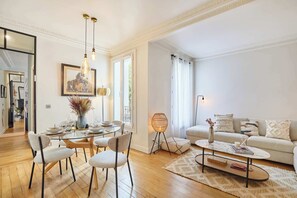 Una sala de estar moderna con una mesa de comedor de vidrio, asientos cómodos, un sofá y una mesa de centro.