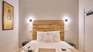 A hotel room with a wooden headboard, white bedding, two bedside tables, and a painting on the wall. - Wonderful Apartment Center of Paris-Montorgueil (Paris)
