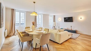 Ein modernes Wohnzimmer mit Essbereich, großen Fenstern und einem Flachbildfernseher.