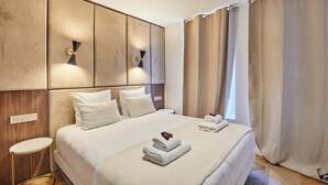 Ein modernes Hotelzimmer mit einem großen Bett, einem Nachttisch und einer Wandleuchte.