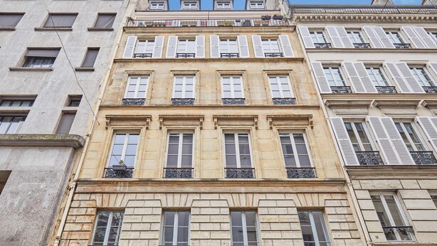 Ein mehrgeschossiges Gebäude im klassischen Stil, mit einheitlichen Fensterdesigns und Balkonen.