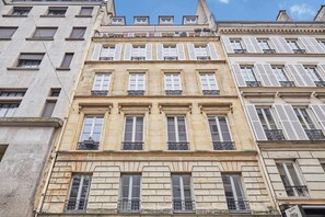 A multi-story building with a classic architectural style, featuring uniform window designs and balconies. - Sublim AC Apartment Opéra Madeleine (Paris)