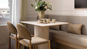 Un salon moderne avec une table ronde, deux chaises, un canapé, un miroir décoratif et une plante en pot.
