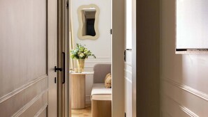 Un couloir doté d’un plancher en bois, de murs blancs et d’un miroir accroché au mur.