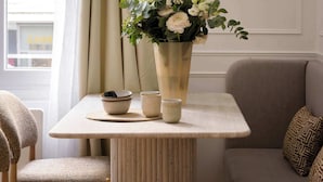 Une pièce comprenant une table, des chaises, un canapé, un miroir et une fenêtre avec des rideaux.