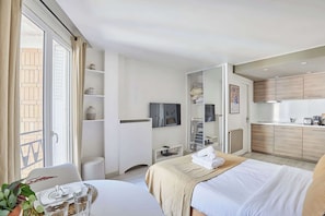 A hotel room with a bed, bedside table, and a small kitchenette. - Charming Suite Champs Elysees Trocadero (Paris)