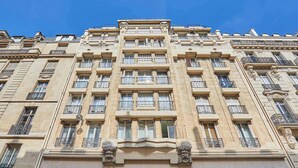 En byggnad med flera våningar i klassisk arkitektonisk stil, med utsmyckade balkonger och dekorativt stenarbete.