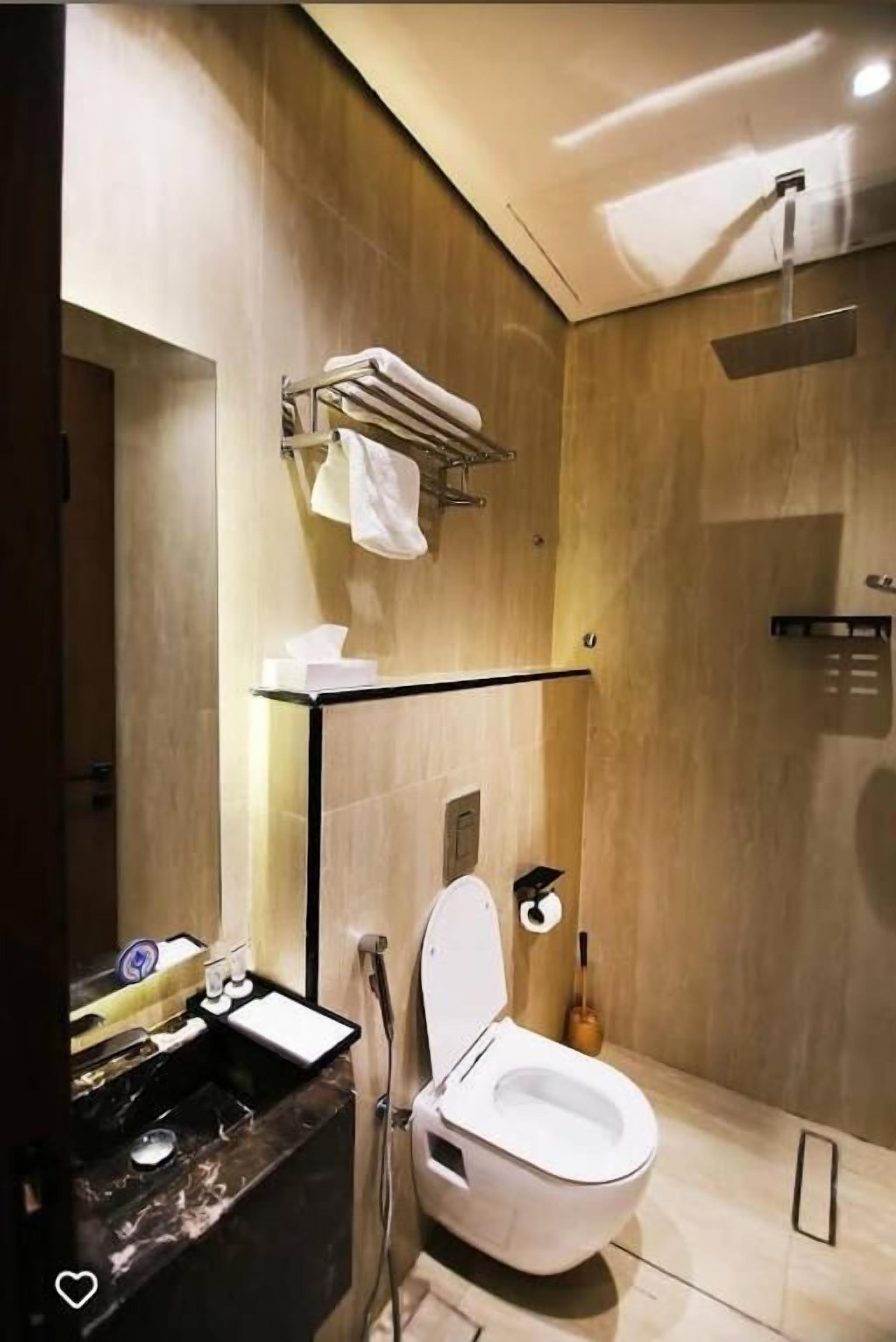 A modern bathroom with a marble sink, a toilet, and a shower.