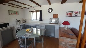 Une cuisine compacte comprenant une table à manger, des chaises, un four à micro-ondes, une machine à café et un évier.