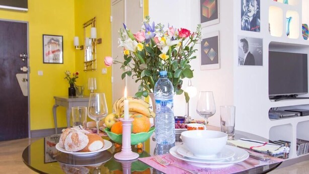 Ein Esstisch mit Glasplatte, eine Blumenvase, eine Wasserflasche und verschiedene Speisen.