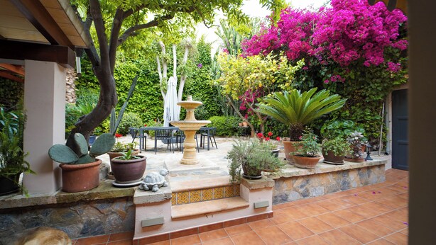 An outdoor patio with a stone fountain, potted plants, and a seating area. - El Jardin de Lara, Casa con Parking Son Españolet-palma (Palma de Mallorca)