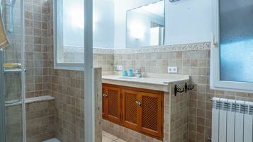 A bathroom with a shower, a sink with a mirror above, and a radiator.