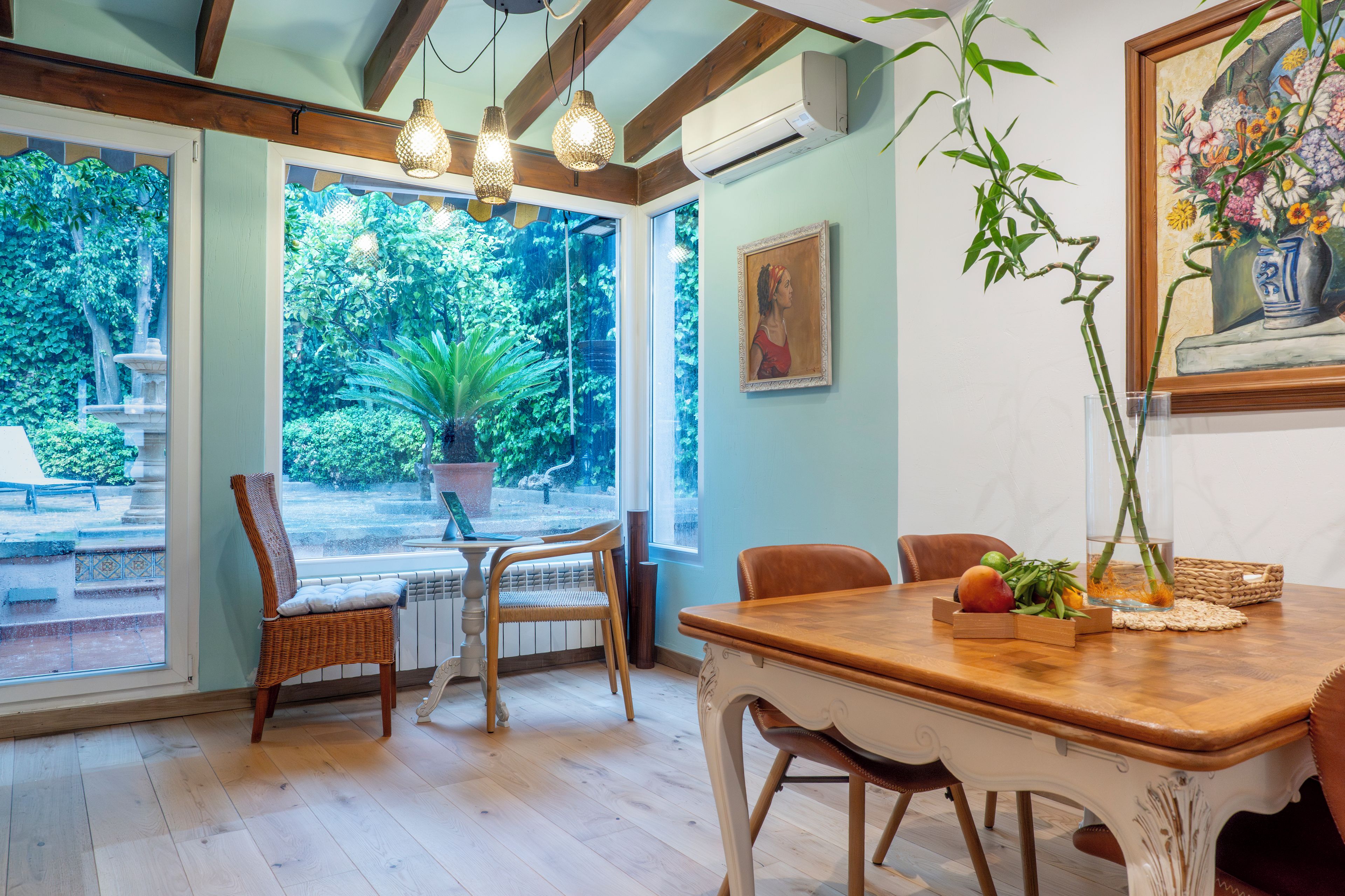 A dining area with a wooden table, wicker chairs, and a view of a garden through large windows. - El Jardin de Lara, Casa con Parking Son Españolet-palma (Palma de Mallorca)