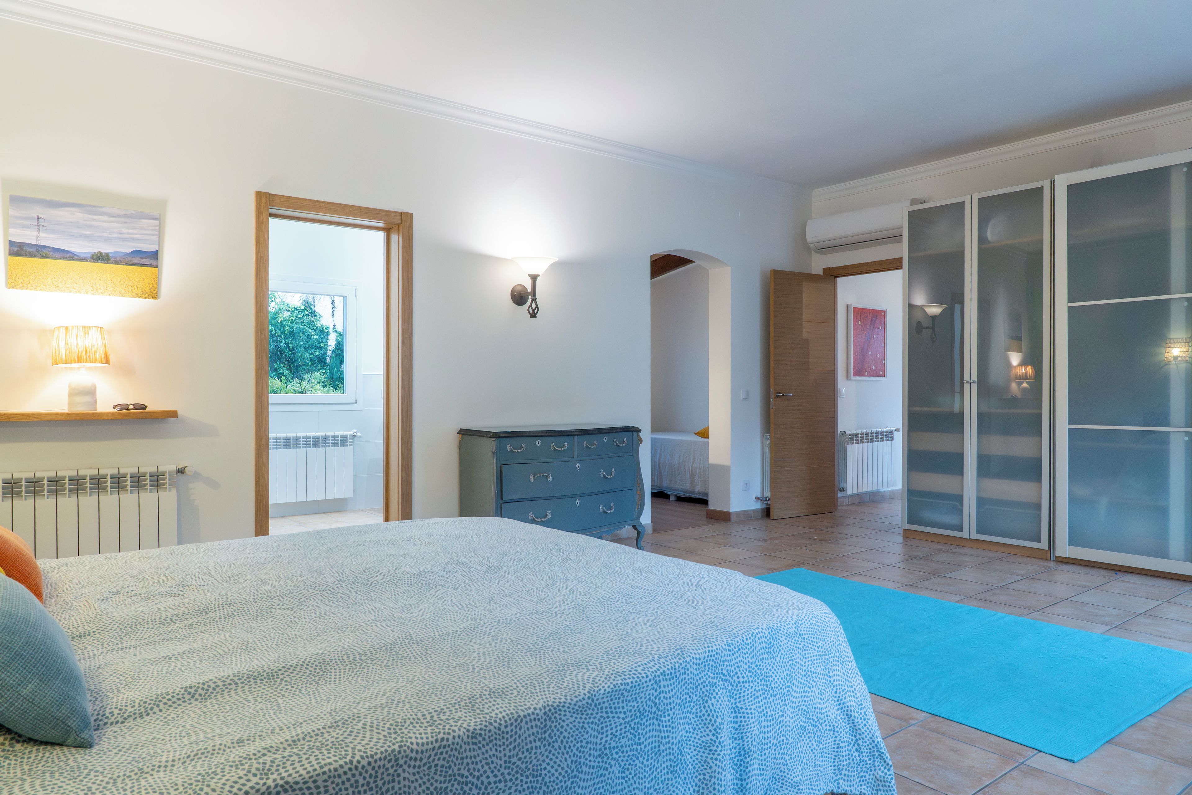 A bedroom with a bed, dresser, and a sliding glass door leading to a balcony.