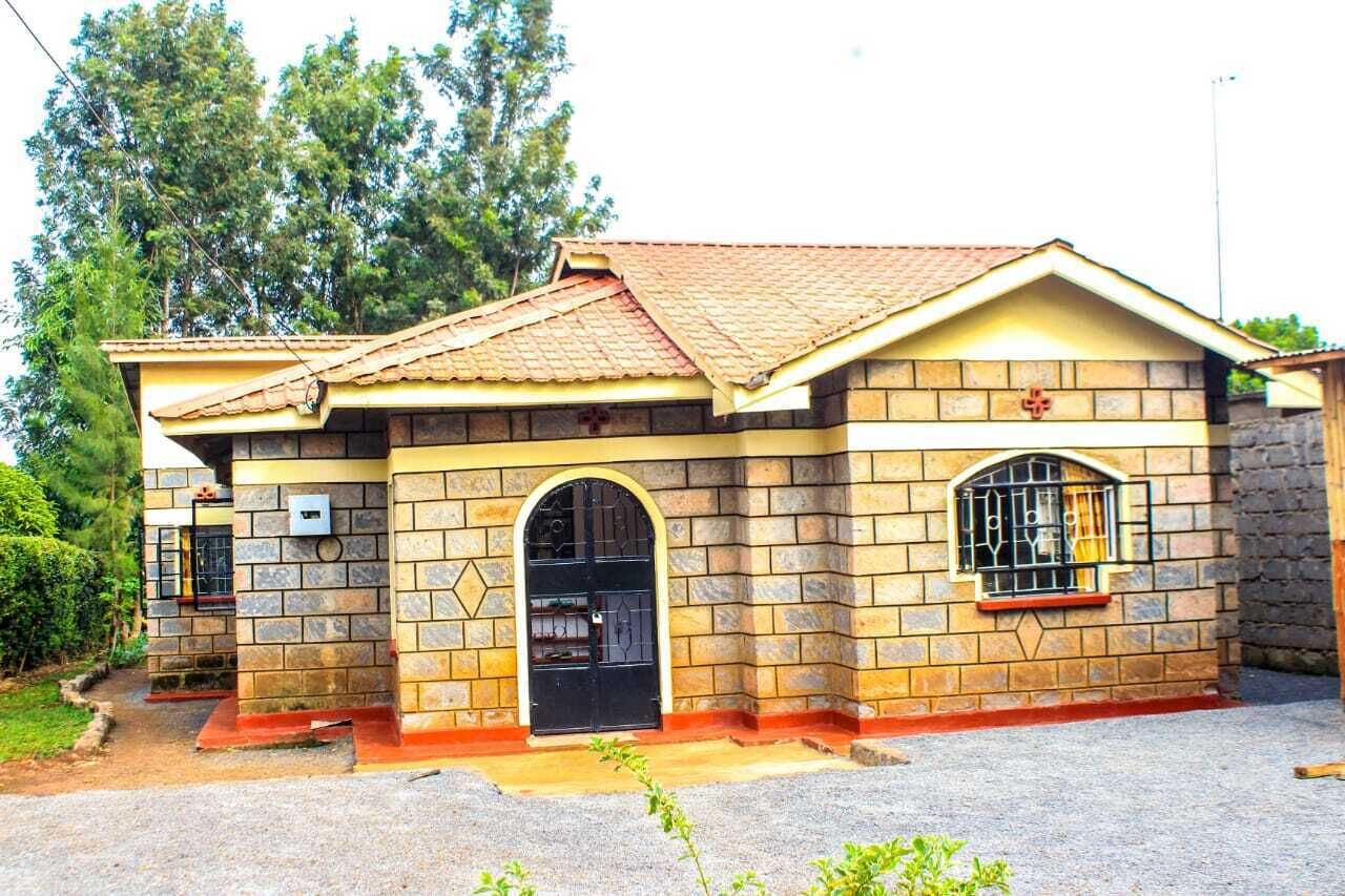 A two-story building with a tiled roof, stone walls, and a central arched doorway.
