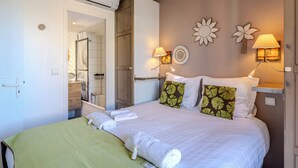 A hotel room with a bed, two wall-mounted lamps, a mirror, and a door leading to a bathroom. - (014) Port Vauban et piscine (Antibes)