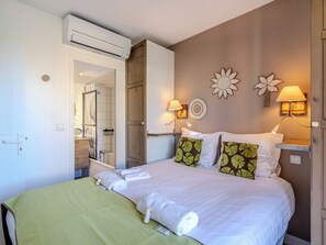 A hotel room with a bed, two wall-mounted lamps, a mirror, and a door leading to a bathroom. - (014) Port Vauban et piscine (Antibes)