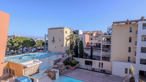 A rooftop pool area with a clear view of the surrounding buildings and a distant cityscape. - (014) Port Vauban et piscine (Antibes)