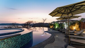 Ein Swimmingpool mit gefliestem Rand, Liegestühlen und Sonnenschirmen.