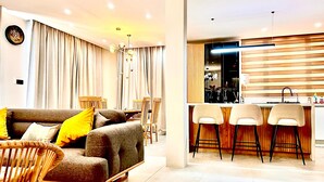 Una sala moderna con un sofá, sillones y una zona de comedor con una mesa y sillas.