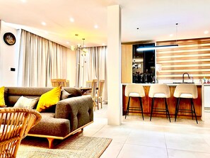A modern living room with a sofa, chairs, and a dining area with a table and chairs. - Exquisite Boho Sunset luxury Suite, Jacuzzi + 2Bed (Flic en Flac)