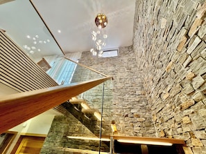 A modern interior with a stone wall, a wooden sloped ceiling, and a hanging light fixture. - Exquisite Boho Sunset luxury Suite, Jacuzzi + 2Bed (Flic en Flac)